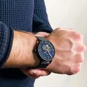 Zwart Pierre Lannier horloge om de pols gedragen, met blauwe wijzerplaat en mesh band.