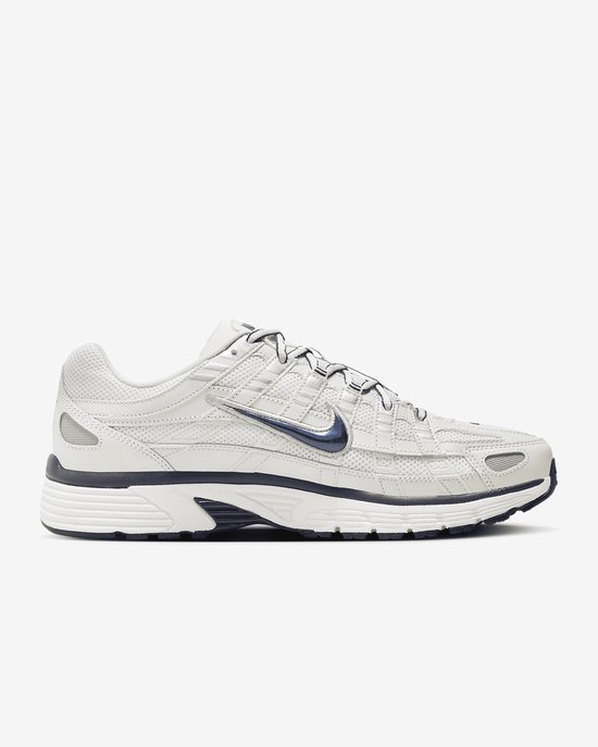 Lichtgrijze Nike P-6000 sneaker met marineblauwe Swoosh en veters. Panelled design met textuur en logo op de zijkant.