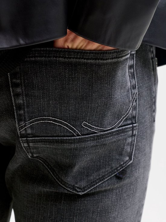Close-up van de achterzak van een grijze jeans met witte stikseldetails.