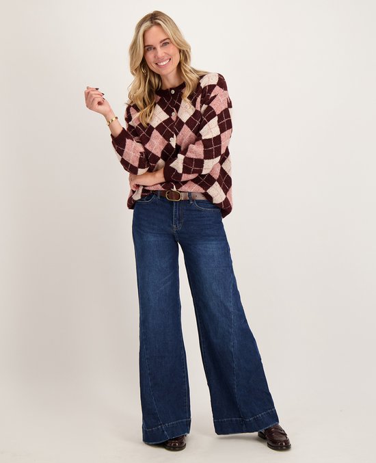 Model draagt een roze en bordeauxrood vest met ruitpatroon en een donkerblauwe wide-leg jeans.
