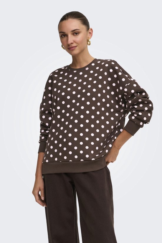 Model draagt een bruine sweater met witte polkadots, gecombineerd met een bruine broek.