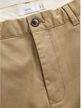 Close-up van de tailleband van een zandkleurige chino met Next-label