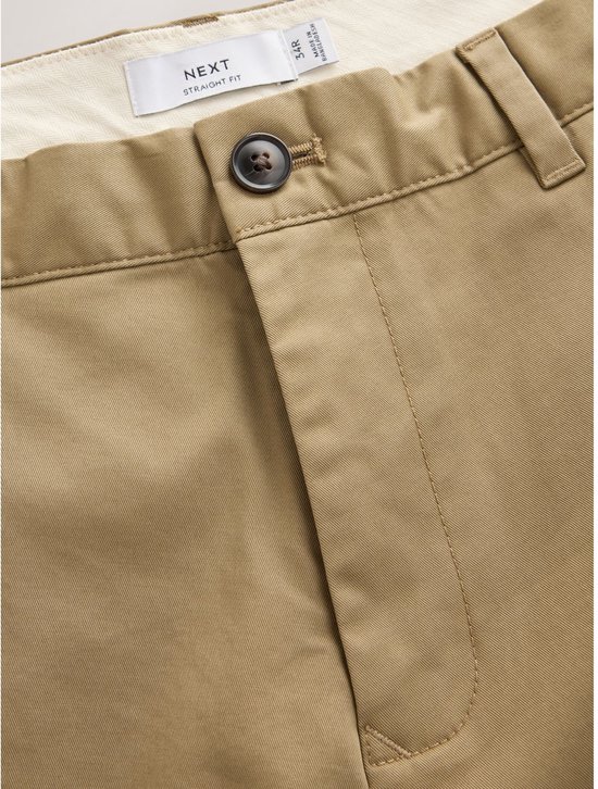 Close-up van de tailleband van een zandkleurige chino met Next-label