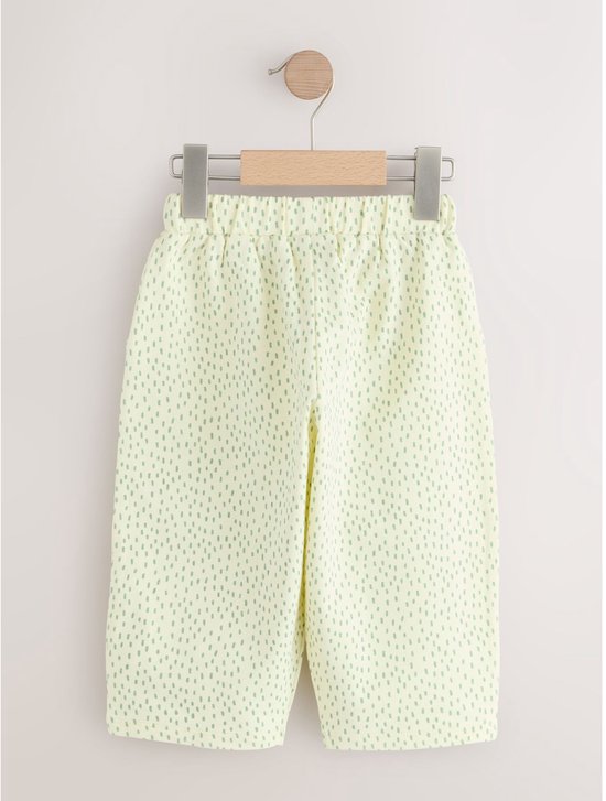 Lichtgele broek met groen stipjespatroon.