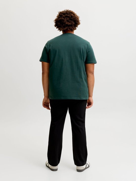 Achterkant van een man in een effen donkergroen T-shirt, staand op een witte achtergrond.
