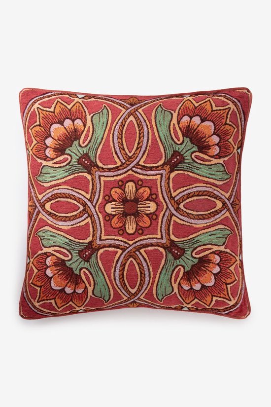 Rood sierkussen met een symmetrisch bloemendessin in oranje, groen en beige.