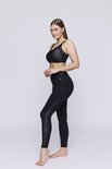 Model in een zwarte sportbeha met geometrische print en bijpassende legging.