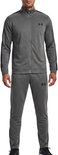 Man met grijze trainingsset: jack met zwarte strepen en logo, en broek met zwarte strepen en logo.