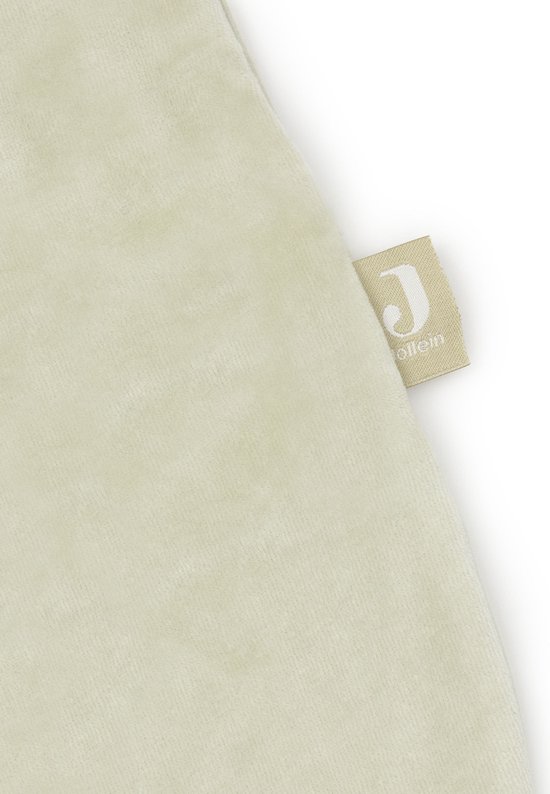 Detail van een lichtgroene velours stof met een geweven Jollein label.