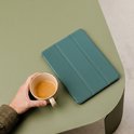 Étui pour tablette vert foncé sur une table vert olive, à côté d'une tasse de café.