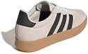 Beige Adidas sneakers met zwarte strepen op de zijkant, van achteren gezien. Zwarte hiel.