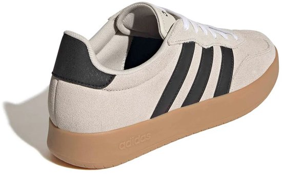 Beige Adidas sneakers met zwarte strepen op de zijkant, van achteren gezien. Zwarte hiel.