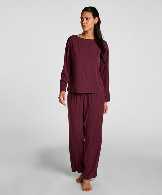 Model van een vrouw in een bordeauxrode pyjamaset met lange mouwen. Ze kijkt naar de zijkant en loopt.