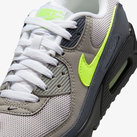 Close-up van de grijze Nike Air Max 90 sneaker met neon groene swoosh en witte veters.