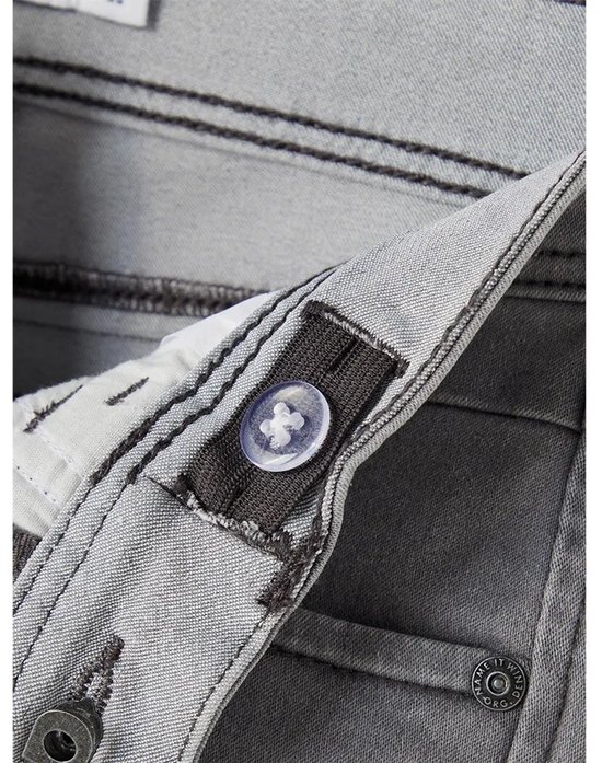 Grijze jeans met donker stiksel en een doorzichtige knoop voor verstelling.
