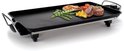 Elektrische grillplaat met verchroomde handvatten, zwart, met gegrilde zalm, biefstuk, courgette en aardappelpartjes.
