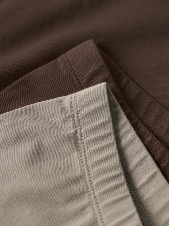 Close-up van de naden van een bruine en taupe legging.