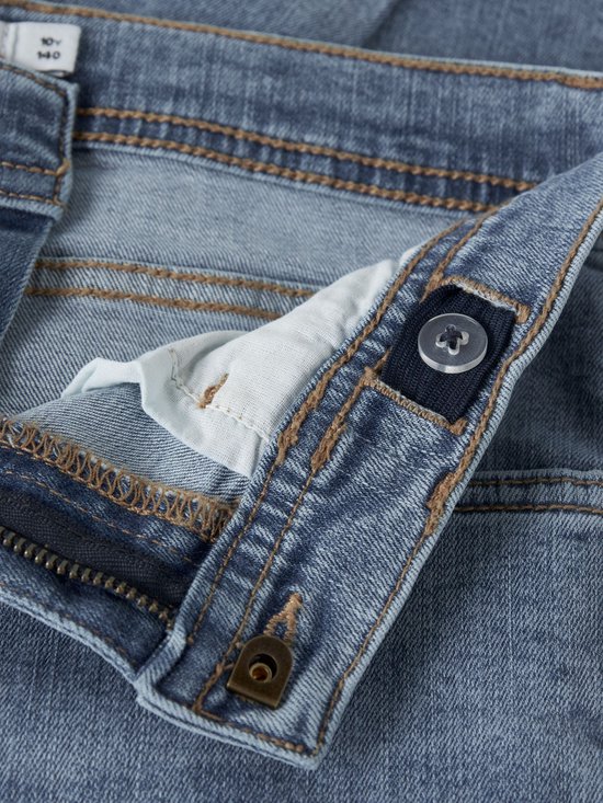 Sluiting van lichtblauwe spijkerbroek met knoop en rits. Verstelbare tailleband aan de binnenkant.