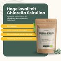 Bruine papieren zak met 'Cupplement Chlorella Spirulina Organic Tablets' label. Groene tabletten en Nederlandse tekst over kwaliteit.