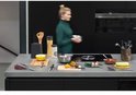 Plan de travail de cuisine avec divers ustensiles, une femme s'éloigne avec un bol.