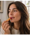 Vrouw met bruin haar brengt Burt's Bees lippenbalsem met granaatappel aan.