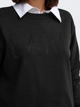 Close-up van een zwarte sweater met "PARIS" opdruk van parels, met wit overhemd.