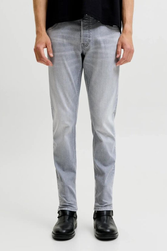 Man staand, frontaal aanzicht van de grijze jeans met rechte pijpen en zwarte schoenen.