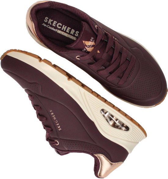 Paar paarse Skechers sneakers met beige zool, gouden accenten en luchtdemping.