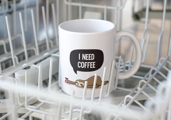 Tasse blanche avec texte 'I NEED COFFEE' et paresseux buvant du café, dans un lave-vaisselle.