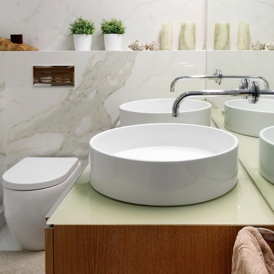 Moderne badkamer met twee ronde witte wastafels, toilet en spiegel. LuxeBath wastafels op houten meubel.