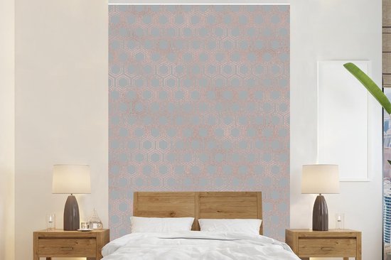 Chambre avec lit en bois et mur d'accent en papier peint gris à hexagones or rose.