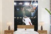 Behang - Fotobehang Een Basketbal speler dunkt de bal in de basket - Breedte 145 cm x hoogte 220 cm