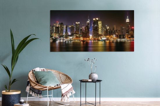 Toile panoramique d'une skyline nocturne de New York, illuminée par d'innombrables gratte-ciel et leurs reflets dans l'eau.