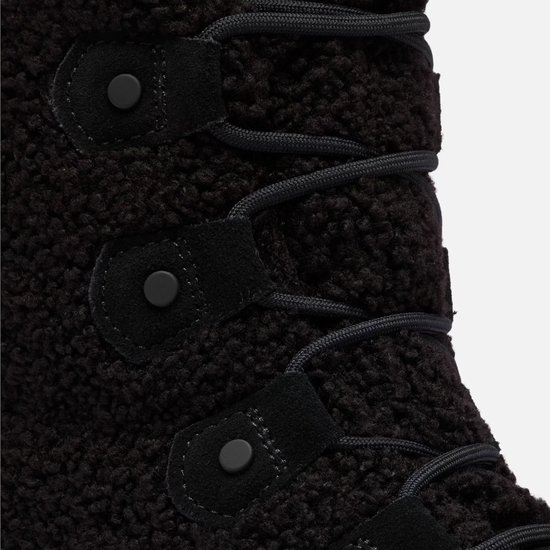 Detail van de vetersluiting en zwarte drukknoppen op de teddy-achtige schacht van een Sorel snowboot.