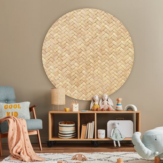 Décoration murale ronde imprimé rotin au-dessus d'une étagère en bois avec jouets et livres.