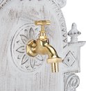 Gouden kraan op een witte muurfontein met sierlijke, verweerde details.