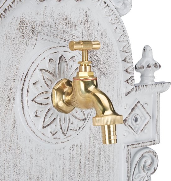 Gouden kraan op een witte muurfontein met sierlijke, verweerde details.