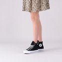Model in een zwarte Converse Chuck Taylor All Star Lift sneakers met witte veters en een dikke witte zool, gecombineerd met een jurk.