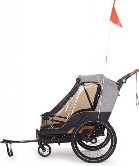 Zijzicht op een fietskar met een oranje vlaggetje, grijs-zwarte stof en bruine details.