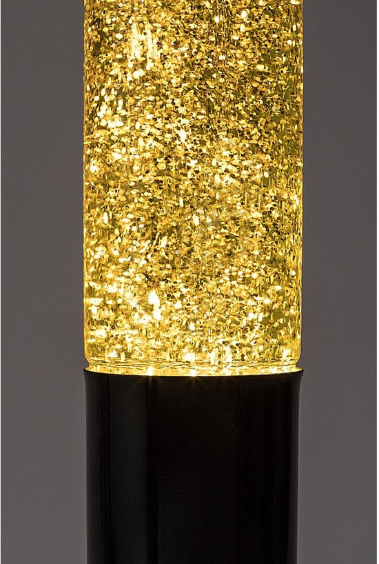 Close-up van de bovenkant van een zwarte lavalamp, met een transparante cilinder vol met gele vloeistof en gouden glitters.