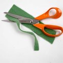 Oranje Fiskars schaar knipt door groen vilt.