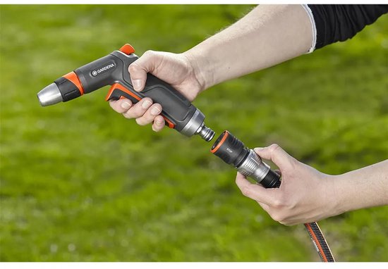 Handen koppelen een GARDENA premium spuitpistool aan een slangstuk met "STOP"-aanduiding.