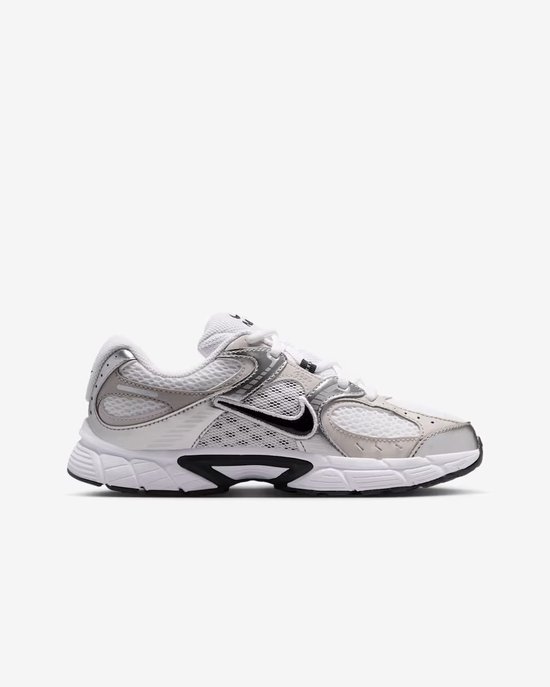 Zij-aanzicht van witte en zilverkleurige Nike sneakers met zwarte Nike swoosh.