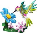 Un colibri LEGO fait de briques vertes, roses et jaunes avec une fleur bleue et une fleur rose.