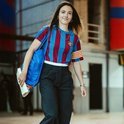 Vrouw draagt een retro FC Barcelona shirt, gestreept blauw en rood, met gele mouwband.