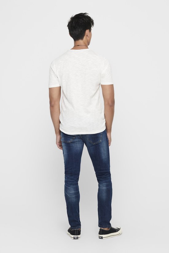 Achterkant van een man in een wit T-shirt en donkerblauwe skinny jeans.