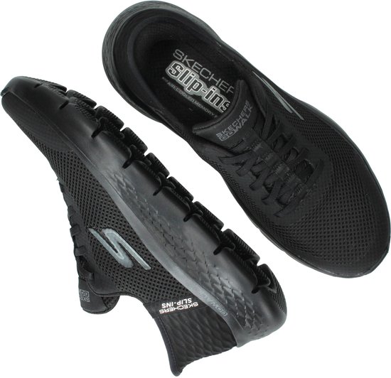 Zwarte Skechers Go Walk instappers, een met zool omhoog, beide met veters.
