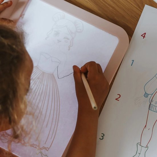 Kind met blonde vlecht tekent prinses op roze lichttablet, met potlood.