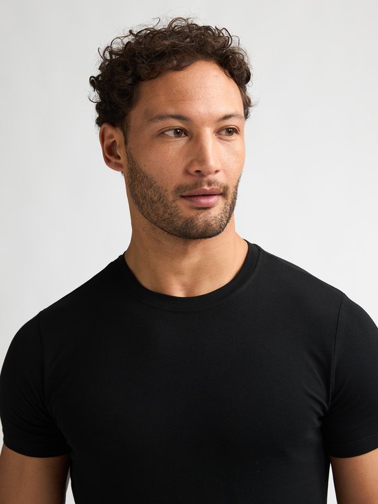 Close-up van man met krullend haar, draagt zwart T-shirt.