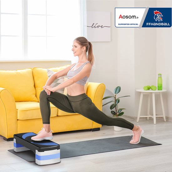 Vrouw in sportkleding stretcht op een zwarte aerobic step met blauwe patronen, in een woonkamer.